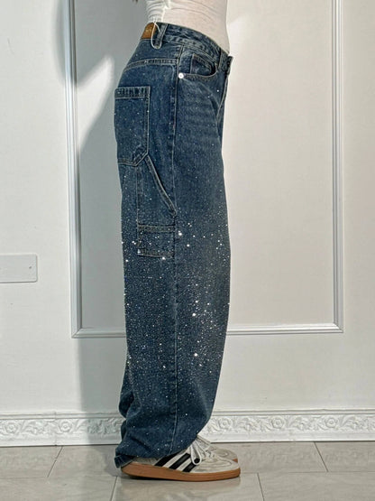 Person wearing blue jeans with glittery accents in a room with white walls and a tiled floor.