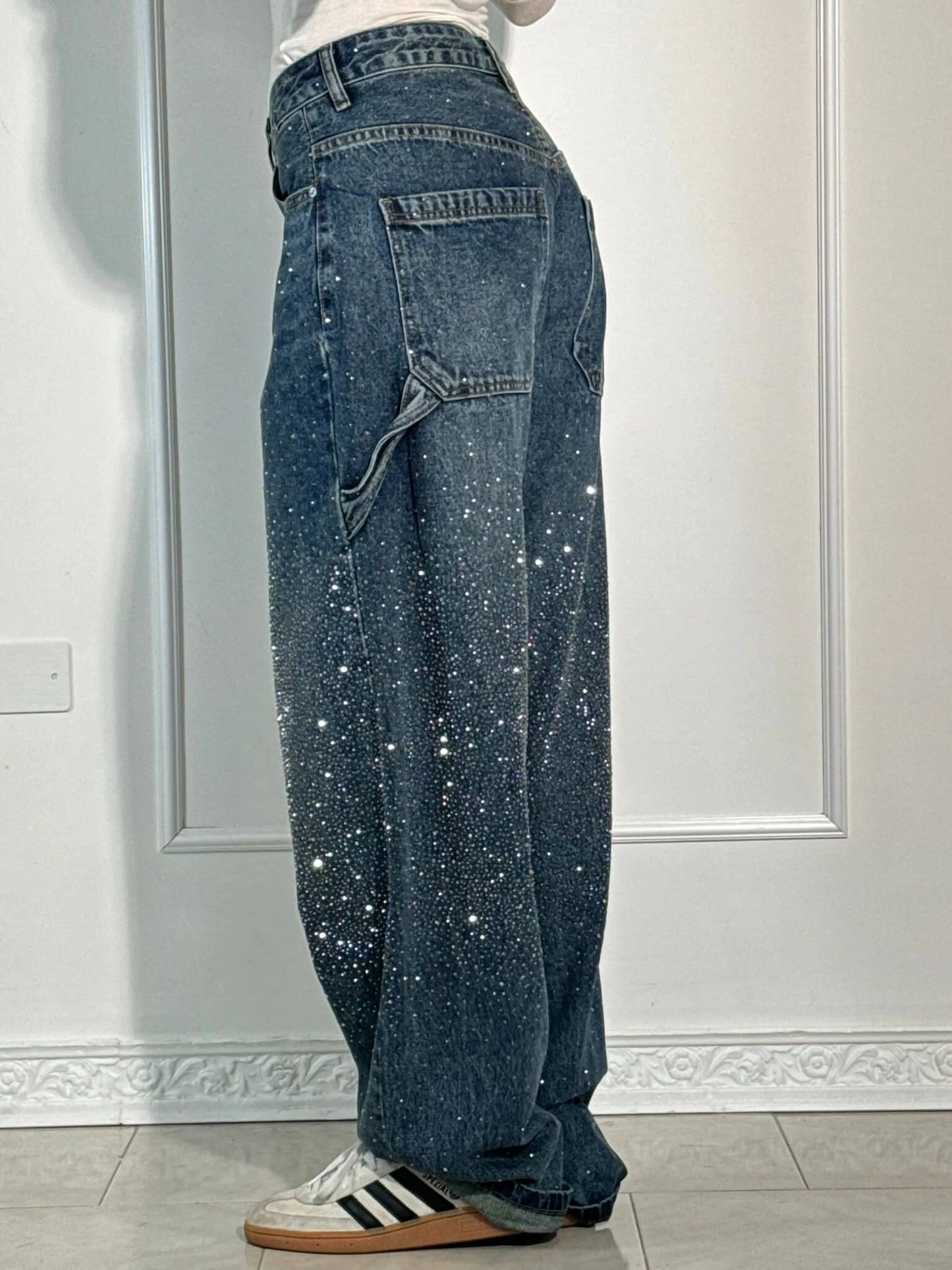 Person wearing blue jeans with star patterns against a white wall.