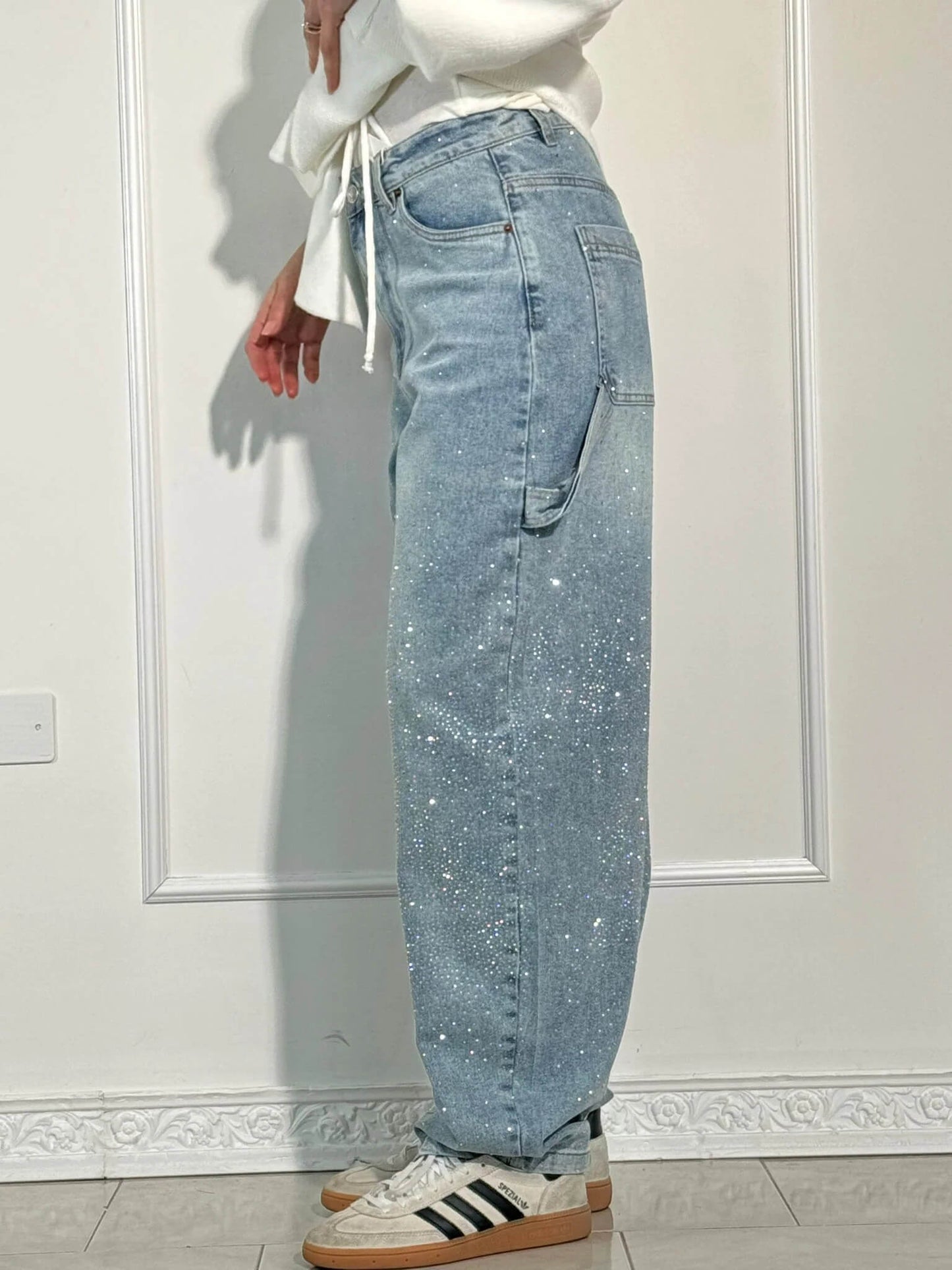 Light blue jeans worn by a person against a white wall.