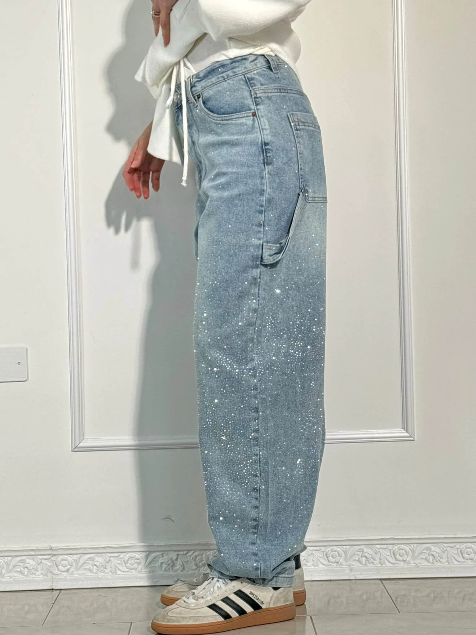 Light blue jeans worn by a person against a white wall.