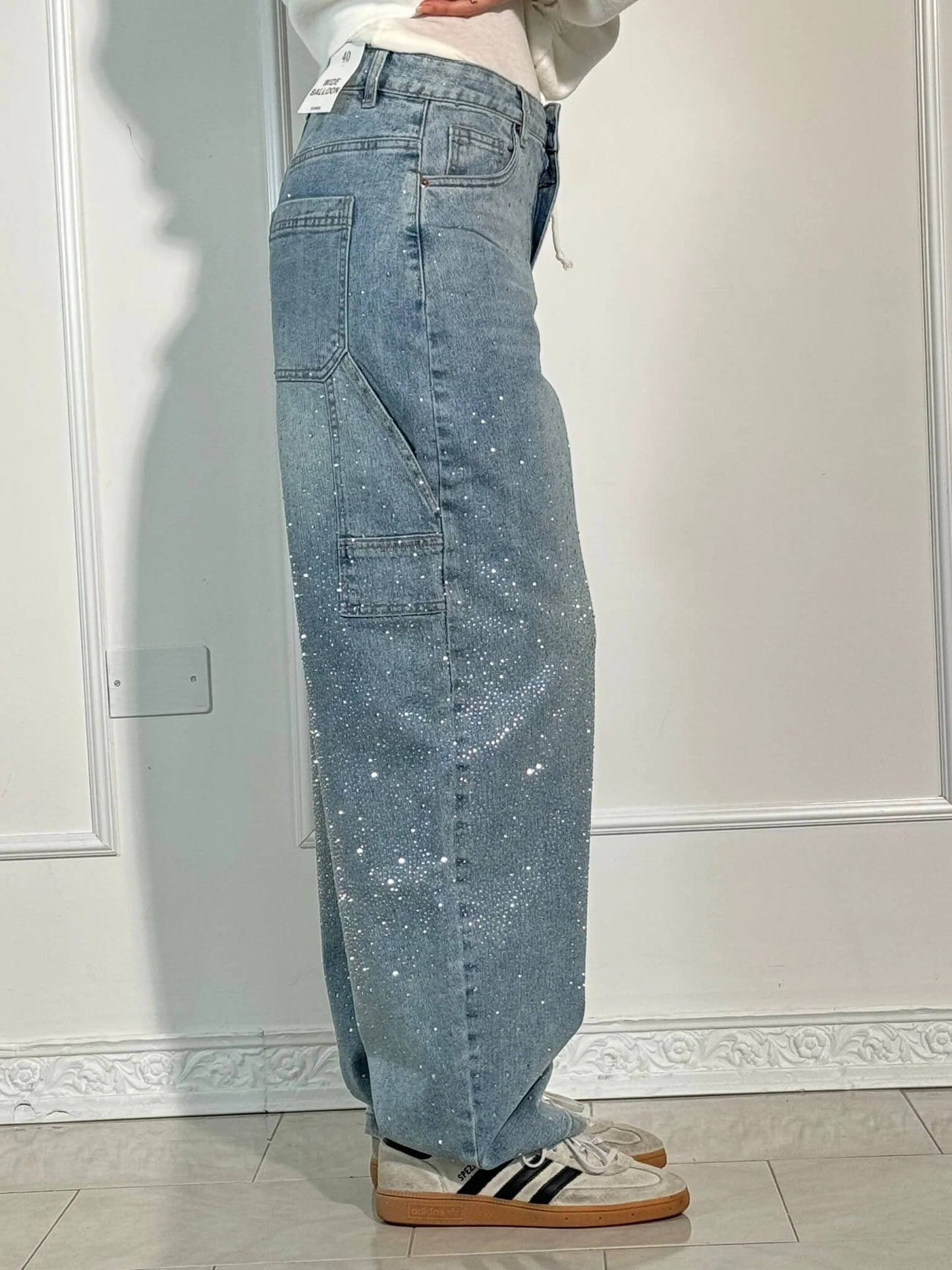 Person wearing light blue jeans with a white wall background