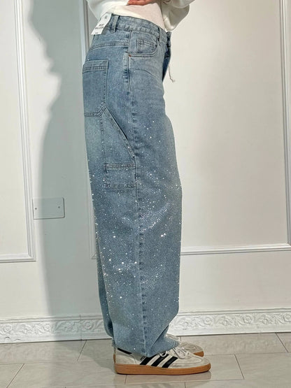 Person wearing light blue jeans with a white wall background