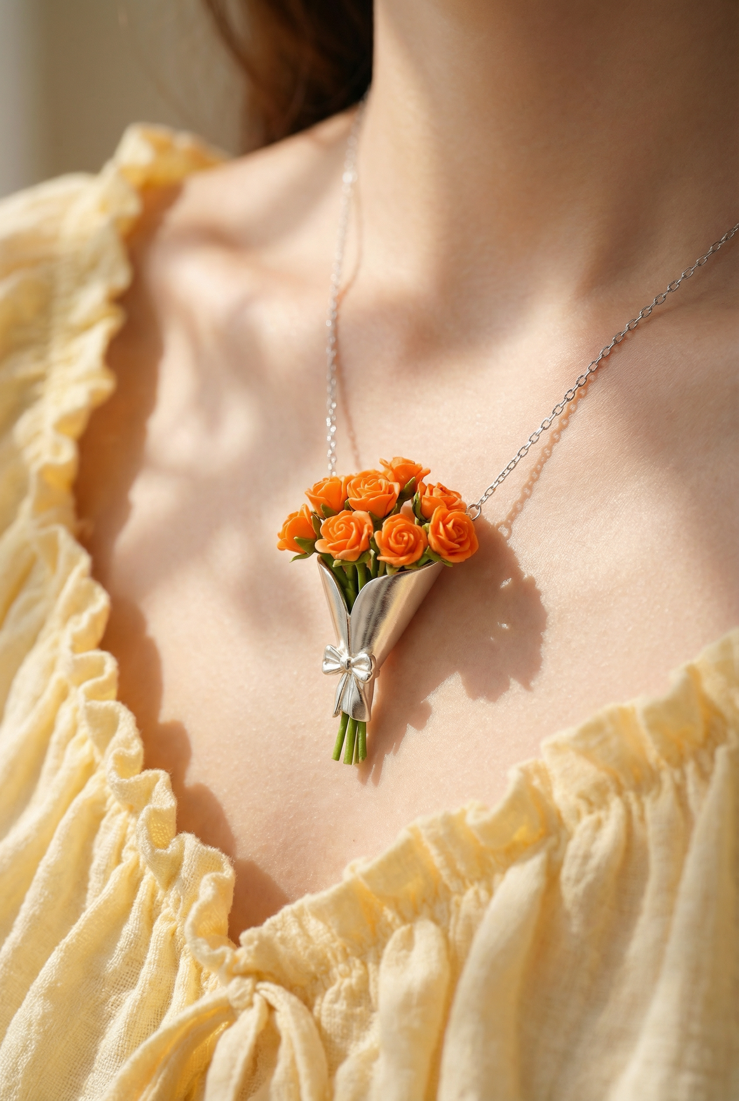 Necklace with a floral pendant worn by a person in a yellow top.