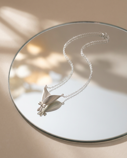 Silver necklace with a butterfly pendant on a reflective surface