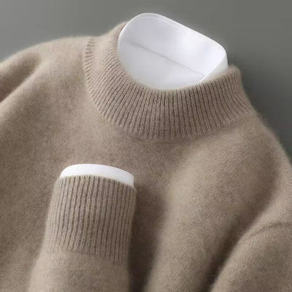 Close-up of a beige sweater with white cuffs and hem on a gray background