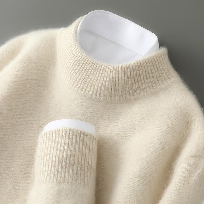 Close-up of a beige sweater with white cuffs and hem against a gray background