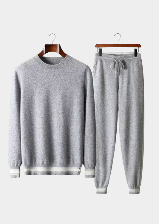 Gray sweater and pants set on hangers against a white background