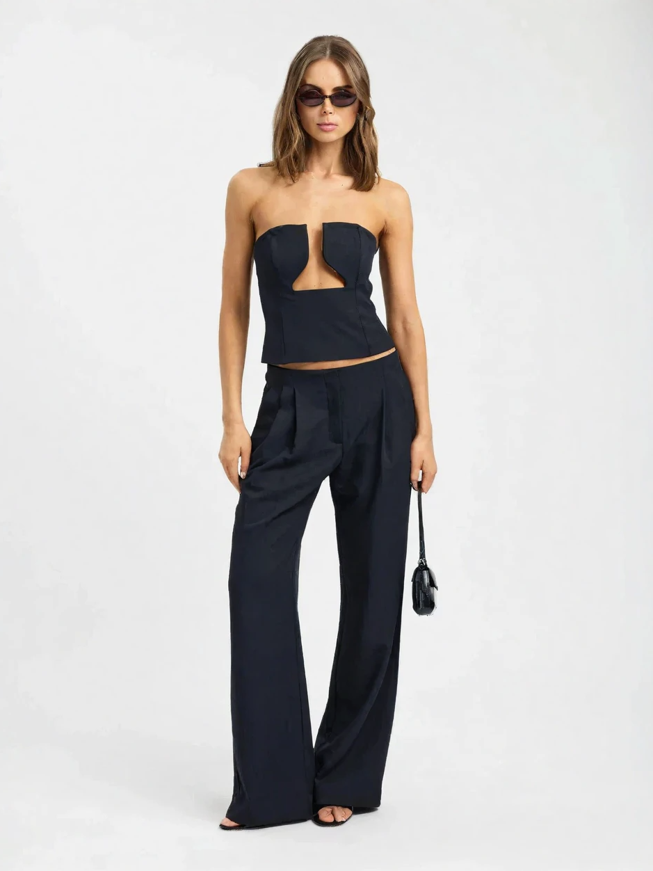Woman wearing a black strapless top and wide-leg pants on a white background