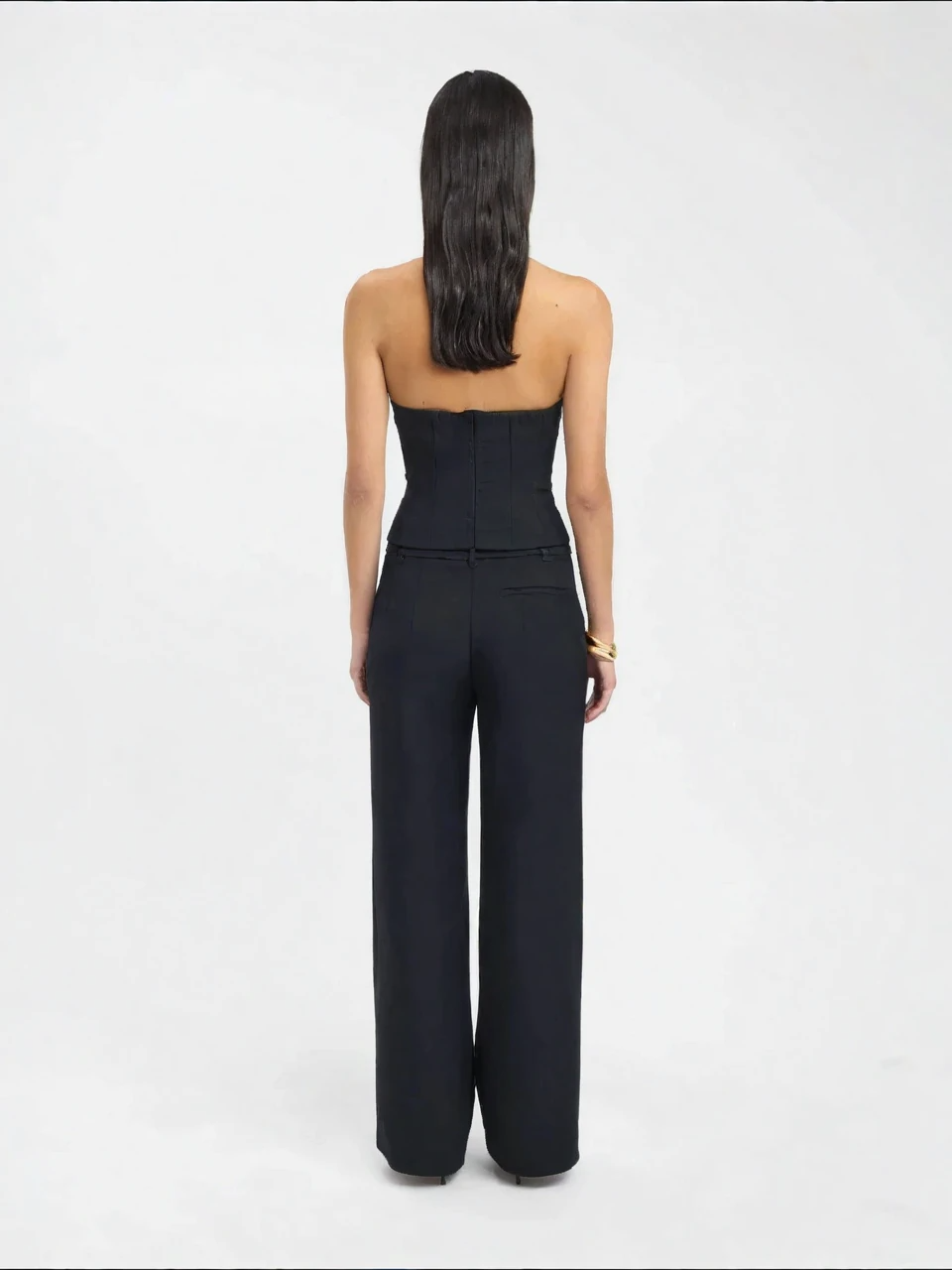 Person wearing a black strapless jumpsuit on a white background