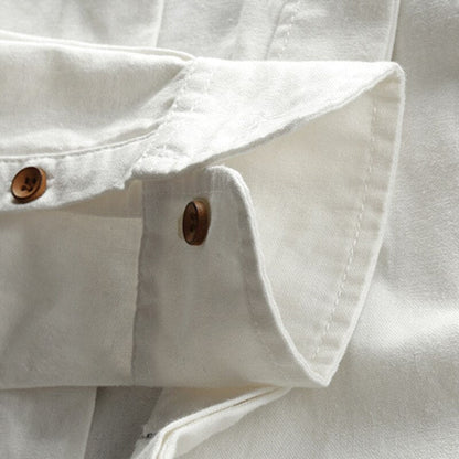 Close-up of a white denim shirt with rolled-up sleeves and brown buttons.