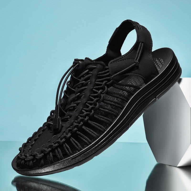Black sandal with braided design on a light blue background