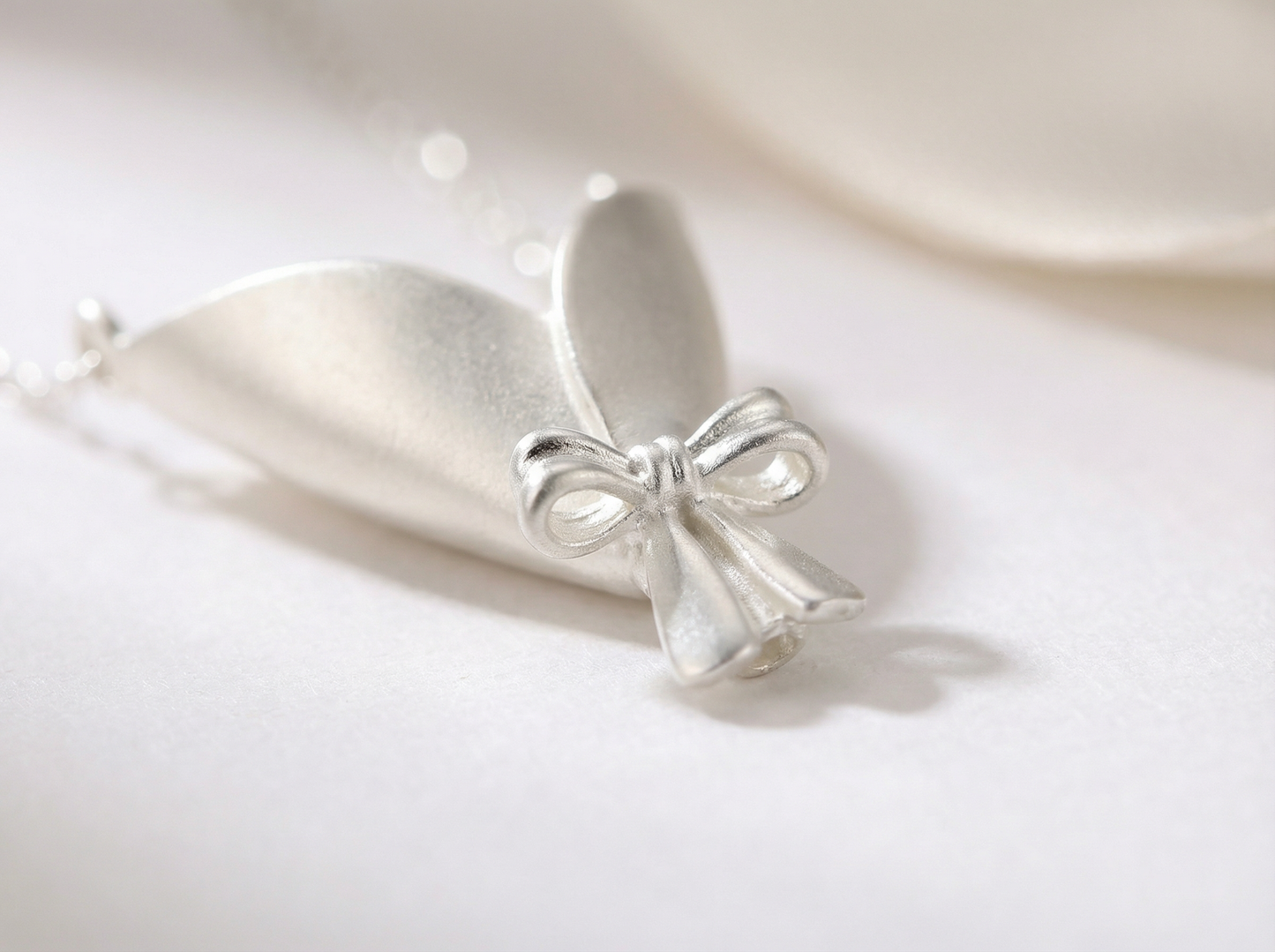 Silver bow-shaped pendant on a white background