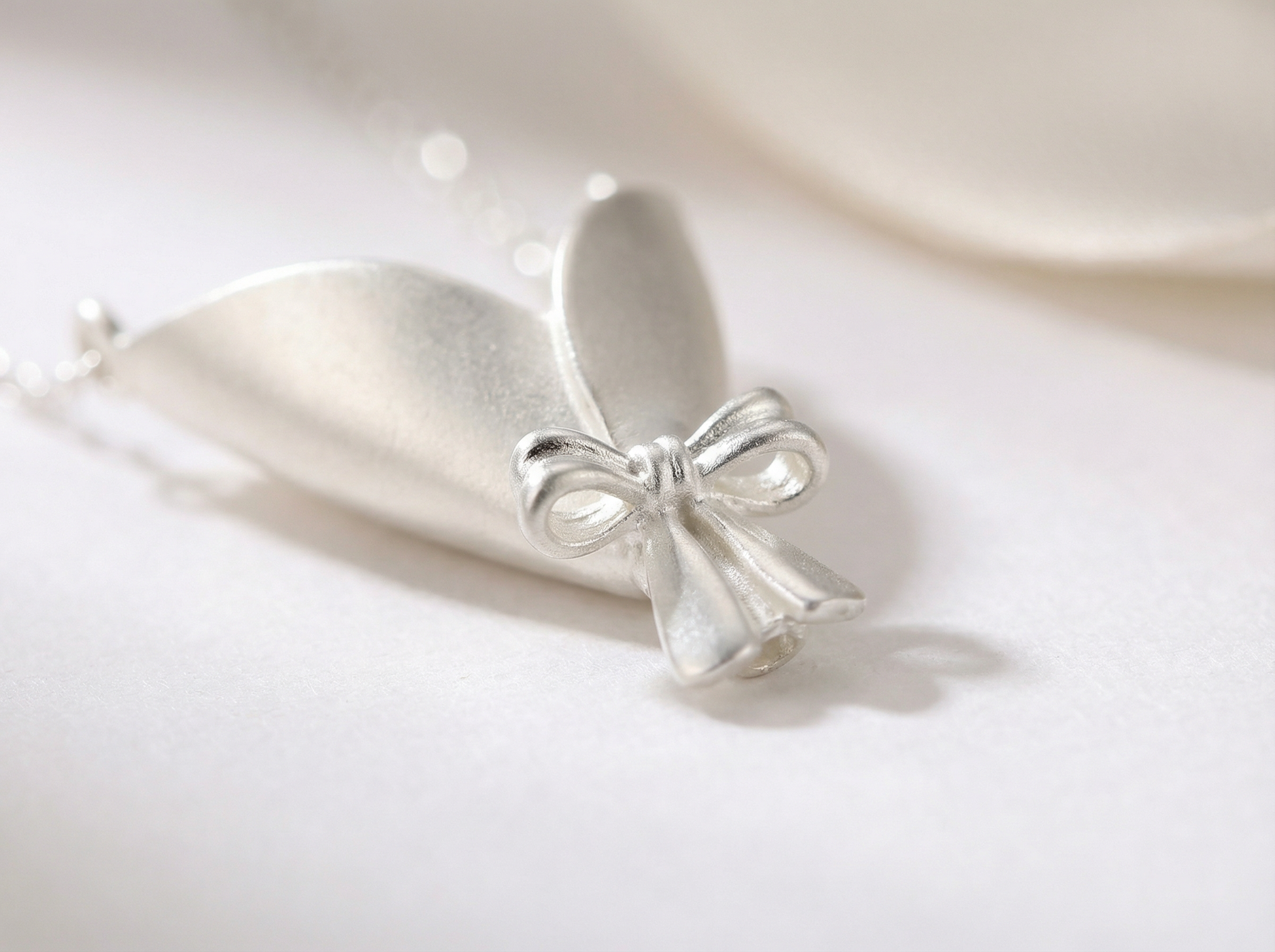 Silver bow-shaped pendant on a white background