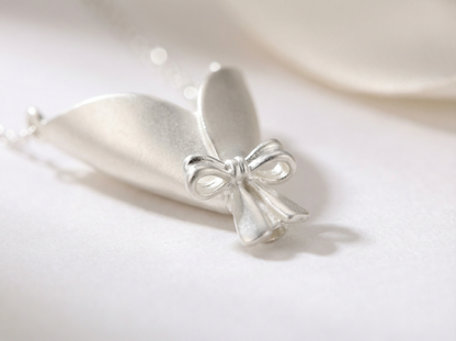 Silver bow-shaped pendant on a white background