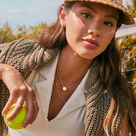Woman holding a tennis ball outdoors with a blurred background