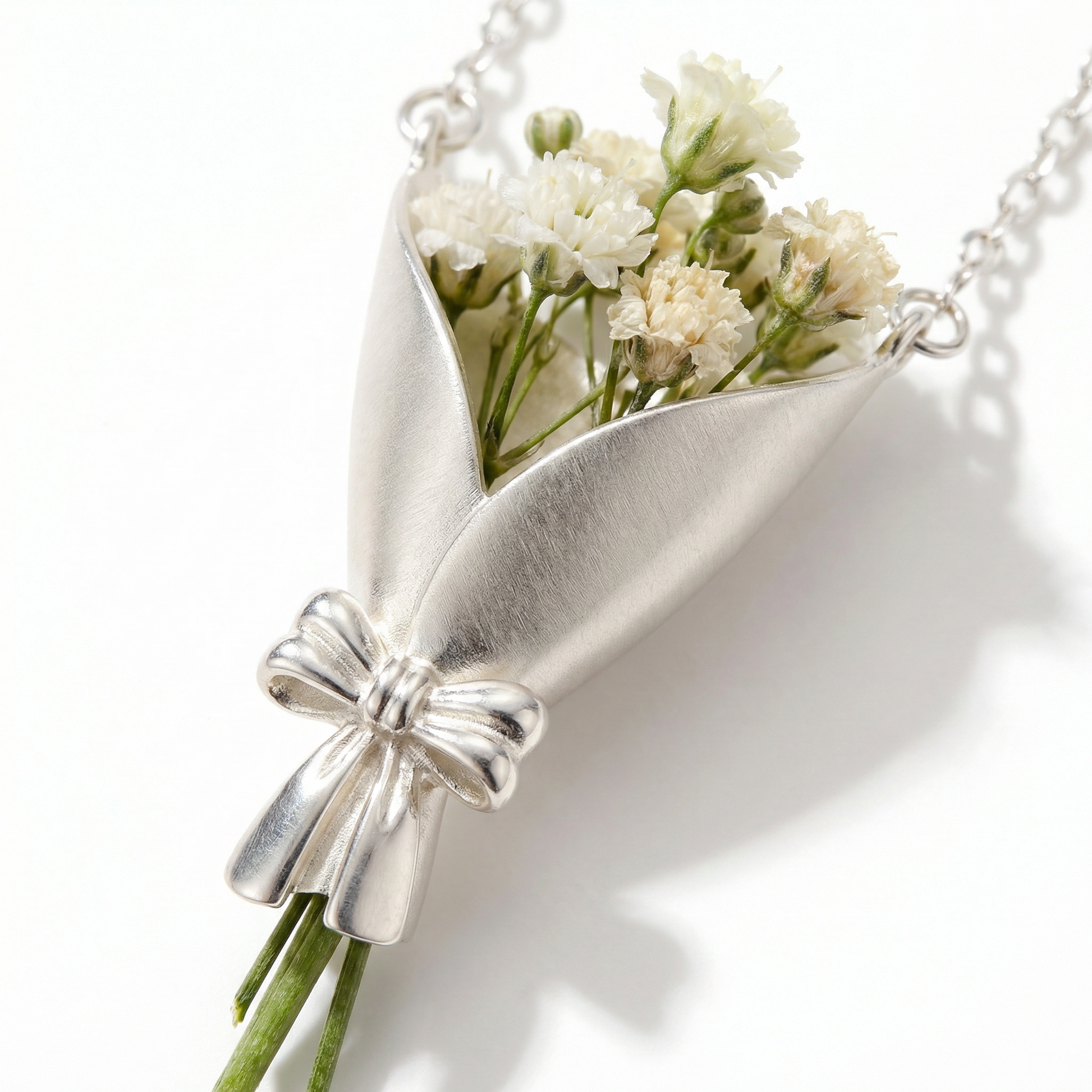 Silver necklace with a bow and small bouquet of flowers on a white background