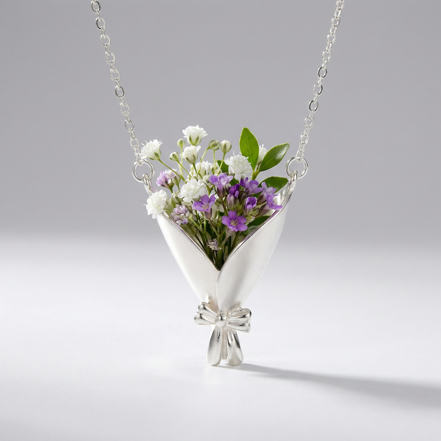 Silver necklace with a floral pendant on a gray background