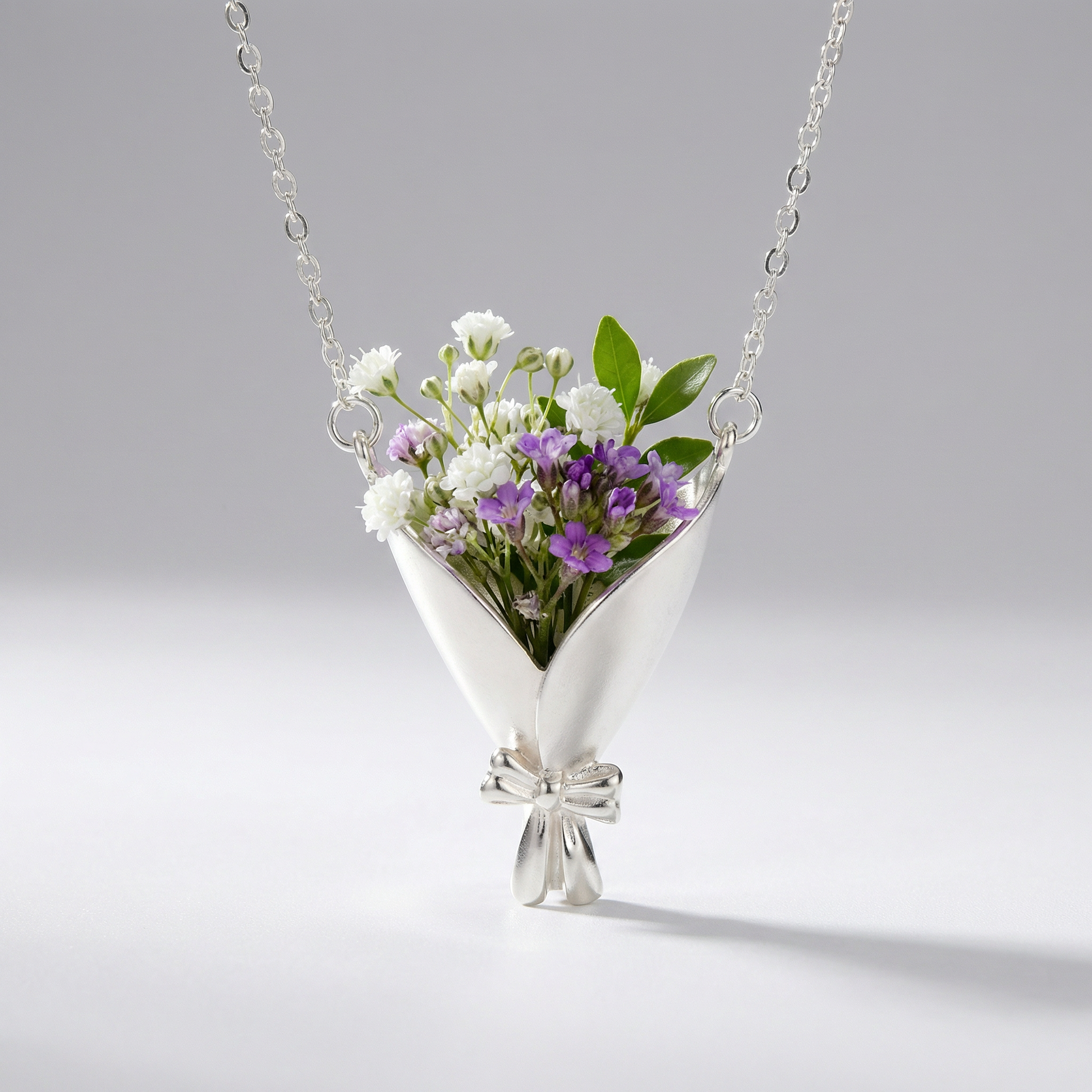 Silver necklace with a floral pendant on a gray background
