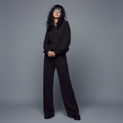 Person wearing a black outfit against a gray background