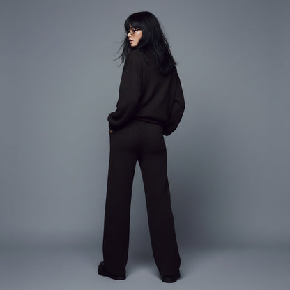 Person wearing a black outfit against a gray background