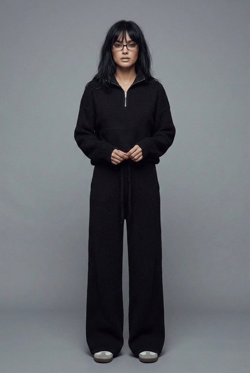 Person wearing a black outfit against a gray background