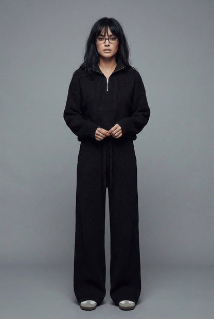 Person wearing a black outfit against a gray background