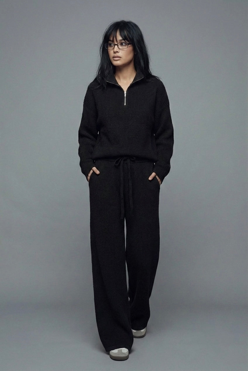 Person wearing a black outfit against a gray background
