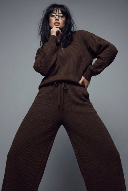 Person wearing a brown sweater and pants against a gray background