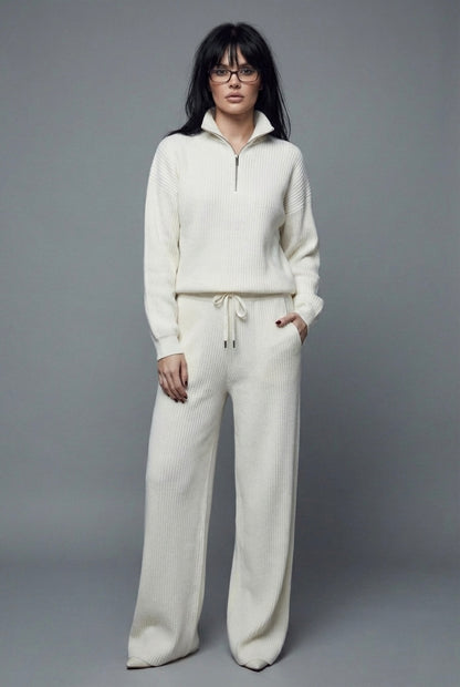 Person wearing a white tracksuit against a gray background