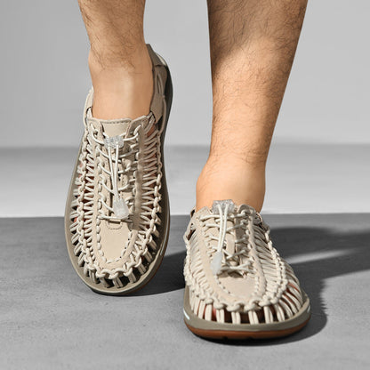 Beige woven sandals worn by a person on a gray background
