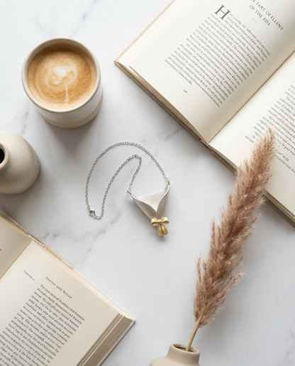 Cup of coffee, open book, necklace, and dried plant on a marble surface
