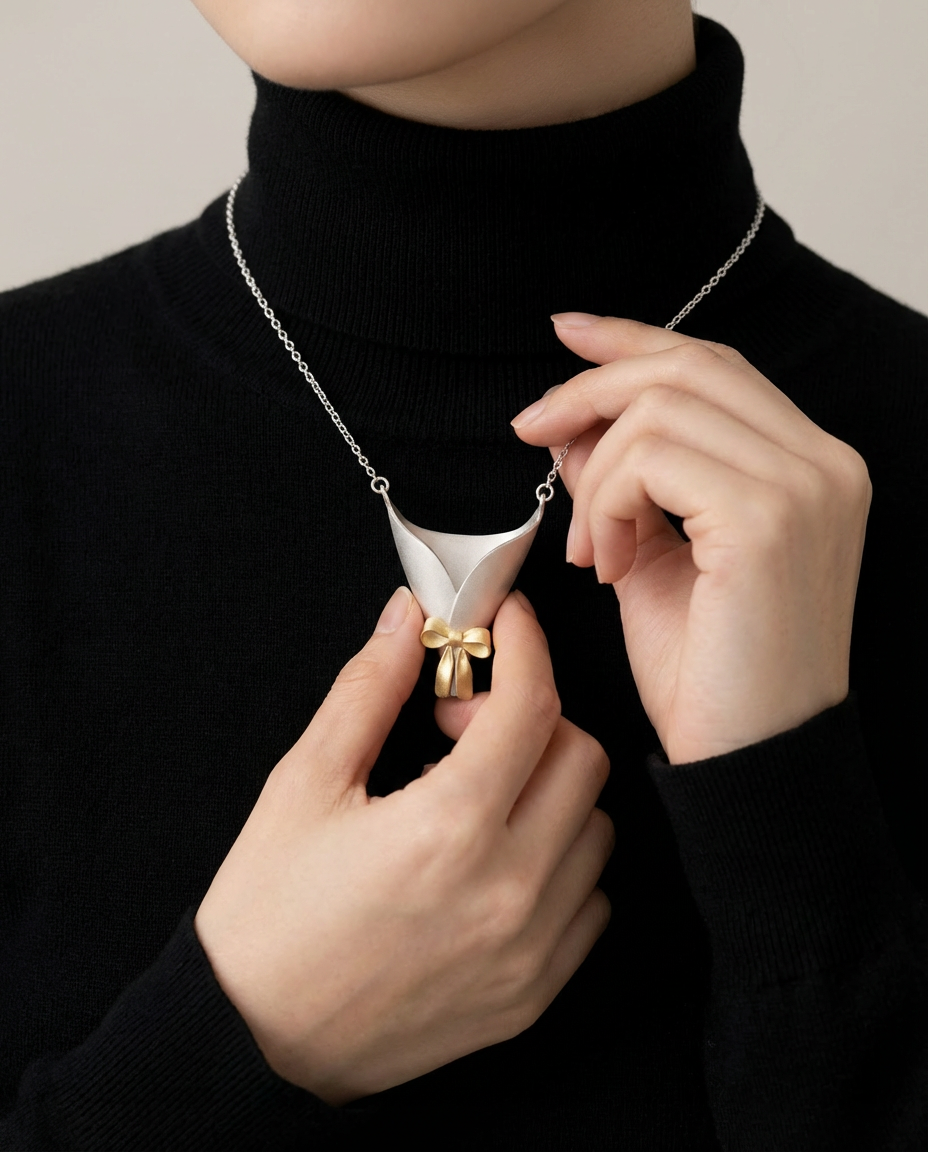 Person wearing a black turtleneck and adjusting a unique necklace with a white pendant and gold accents.