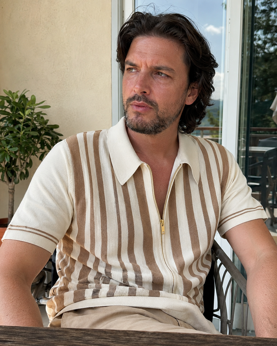Sunny patio style photo of a man aged around 28 to 38 wearing the Riviera striped knit zip polo