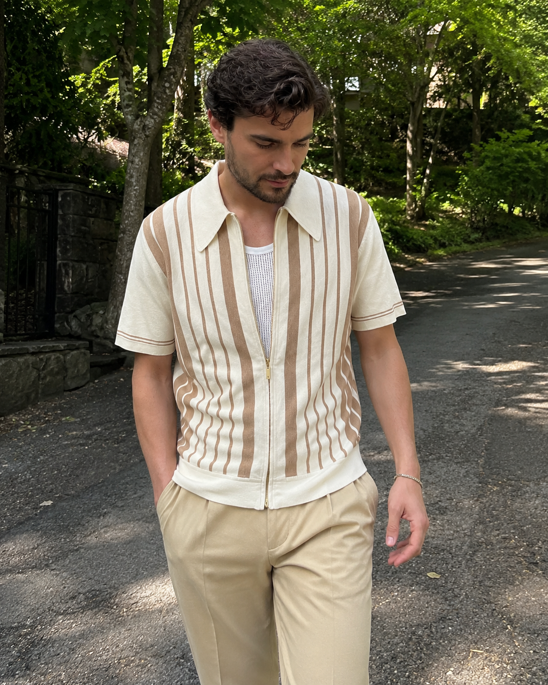 Garden path style photo of a man aged around 28 to 38 wearing the Riviera striped cotton knit zip polo