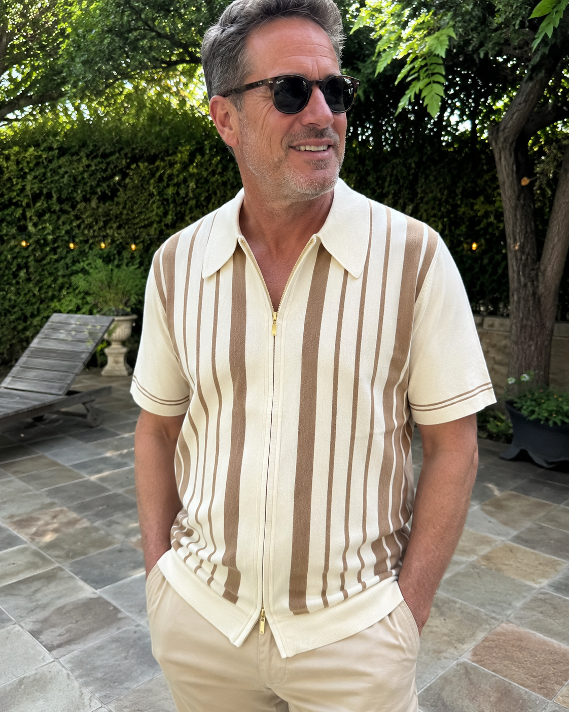 Garden sunshine style photo of a man over 40 wearing the Riviera striped cotton knit zip polo